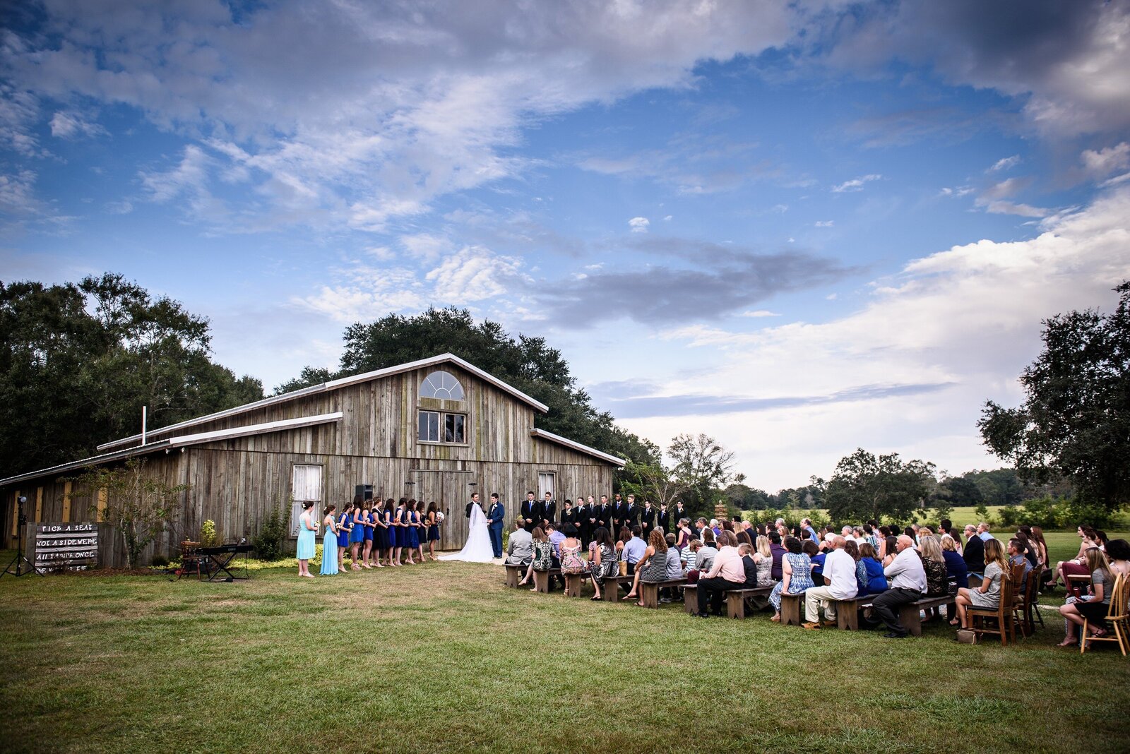 Norris Oaks Picayune wedding ceremony in front of barn with blue sky