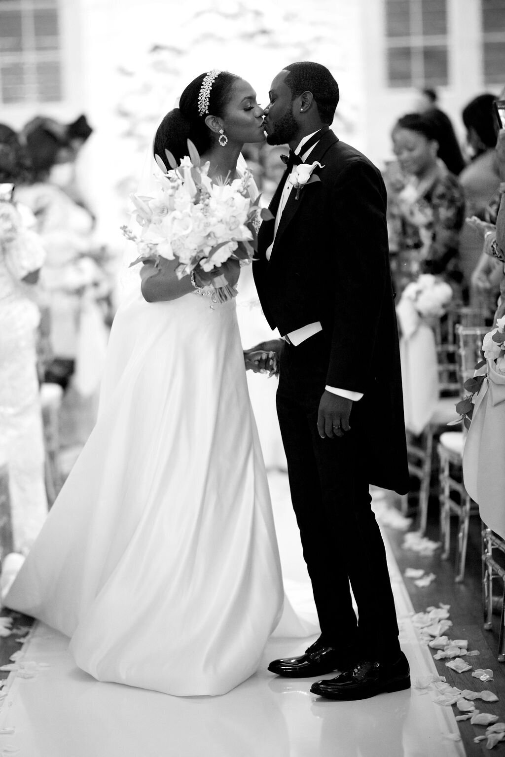 black and white photo bride and groom kissing and standing in the church aisle