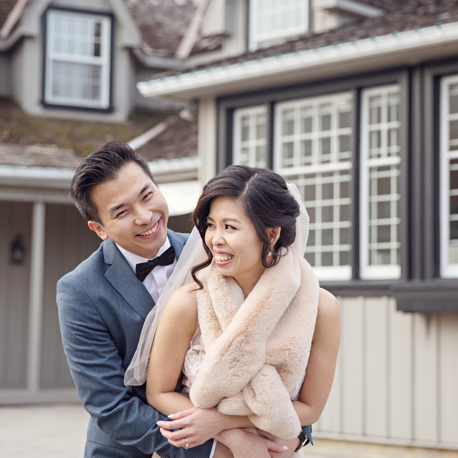wedding couple smiling with fur wrap in front of buildings