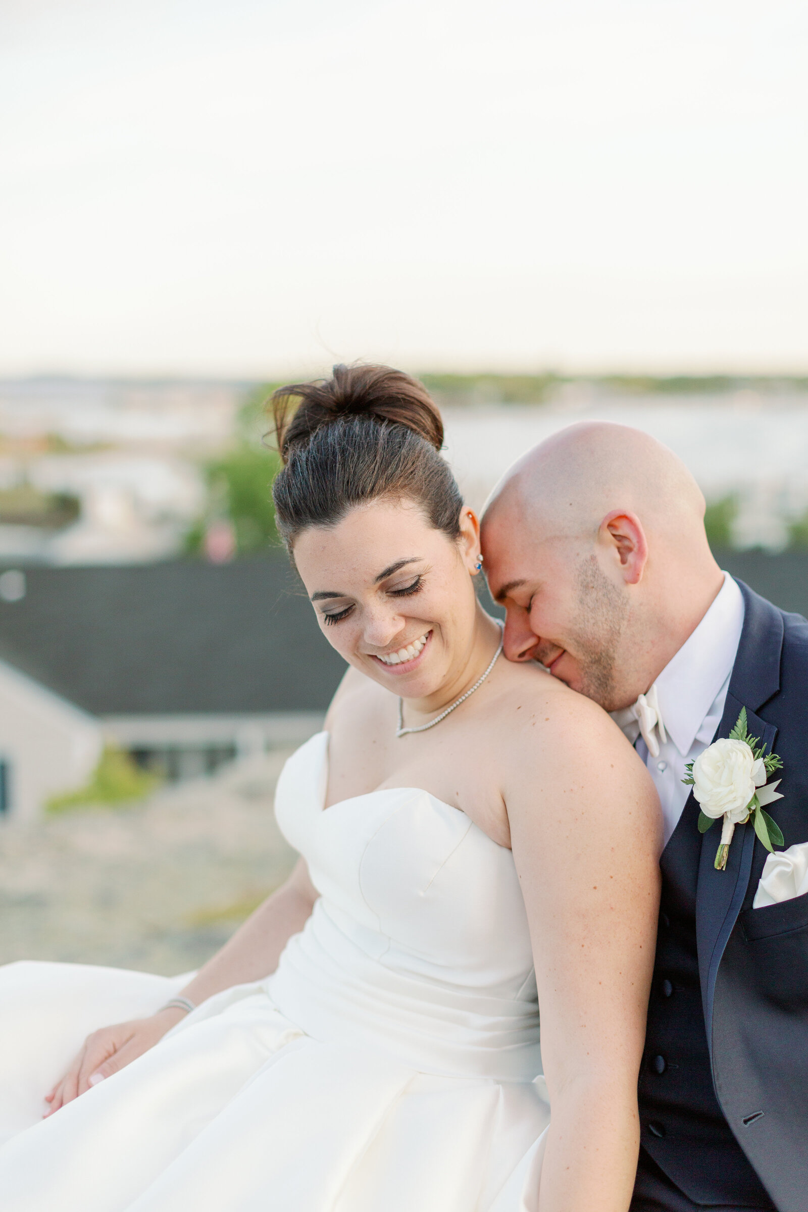 A bride and groom sitting together while he rests his head on her shoulder.