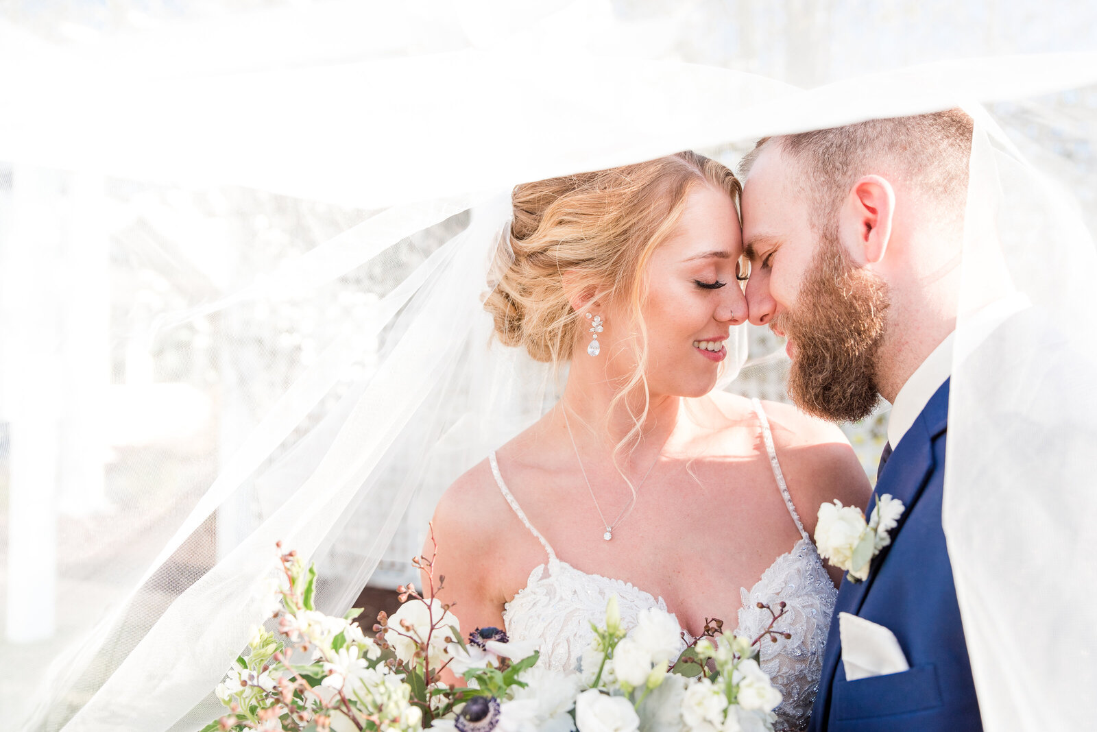 couple touching noses under wedding veil
