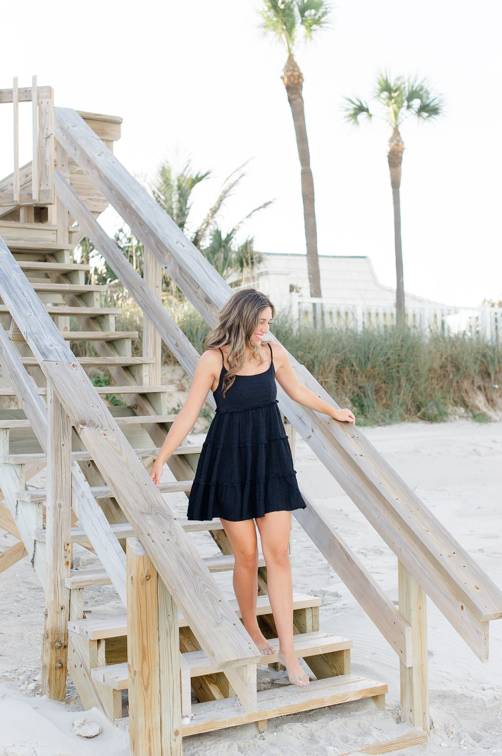 Senior girl walking down a beach staircase during her senior portraits