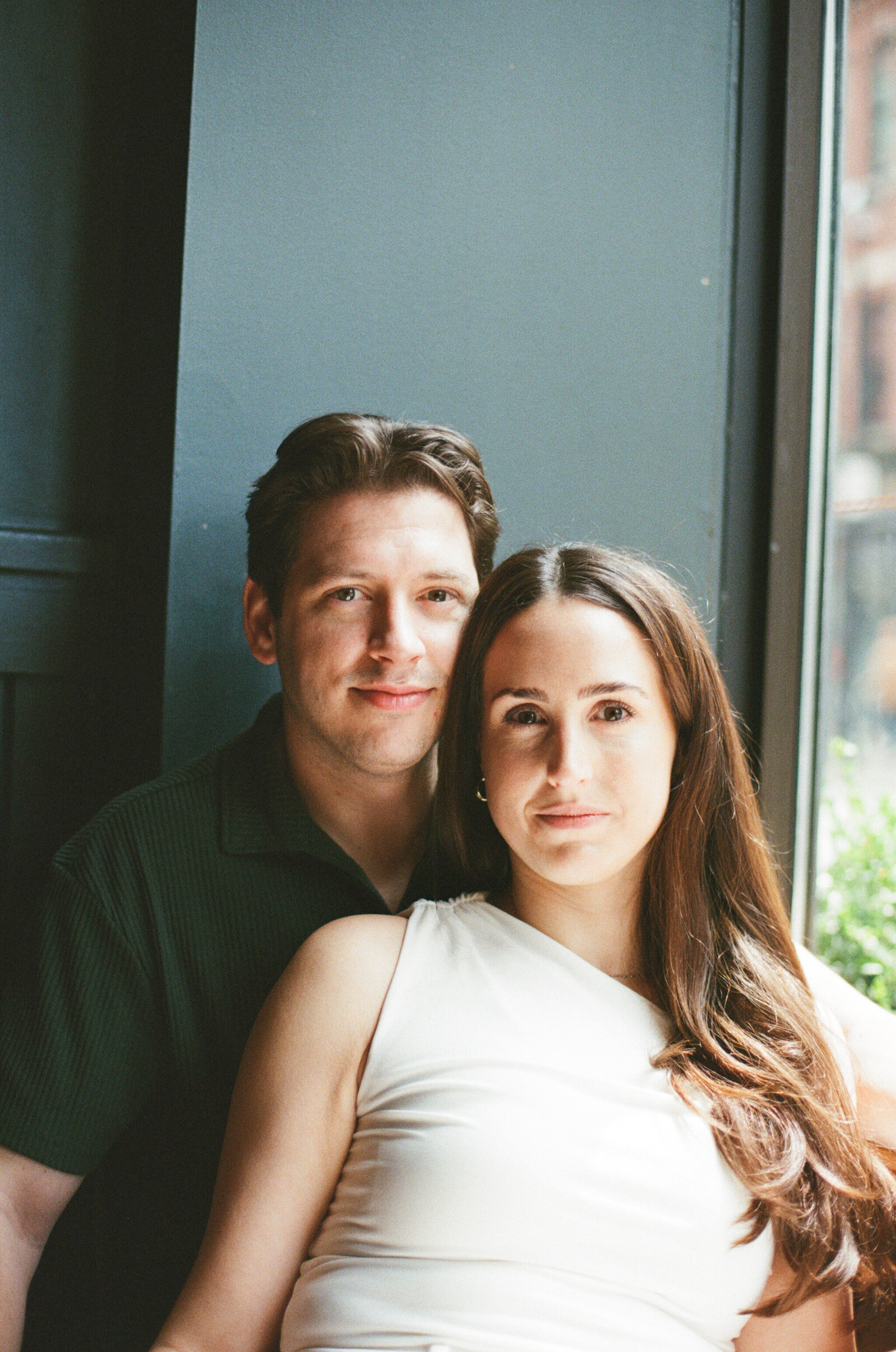 A couple sits together in the nook of a local bar in downtown Halifax for their engagement session. 