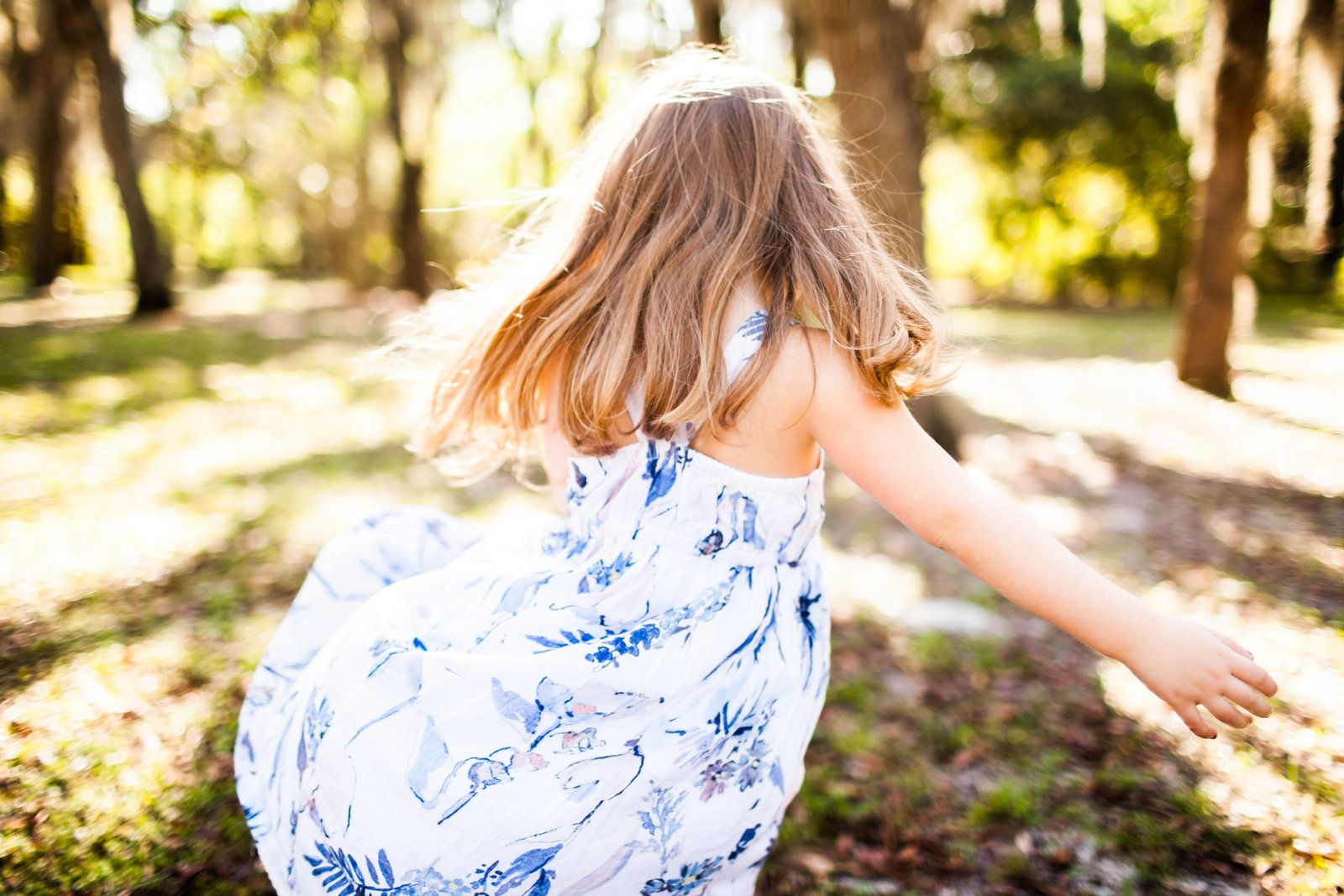 Little girl twirling in boho dress in the woods