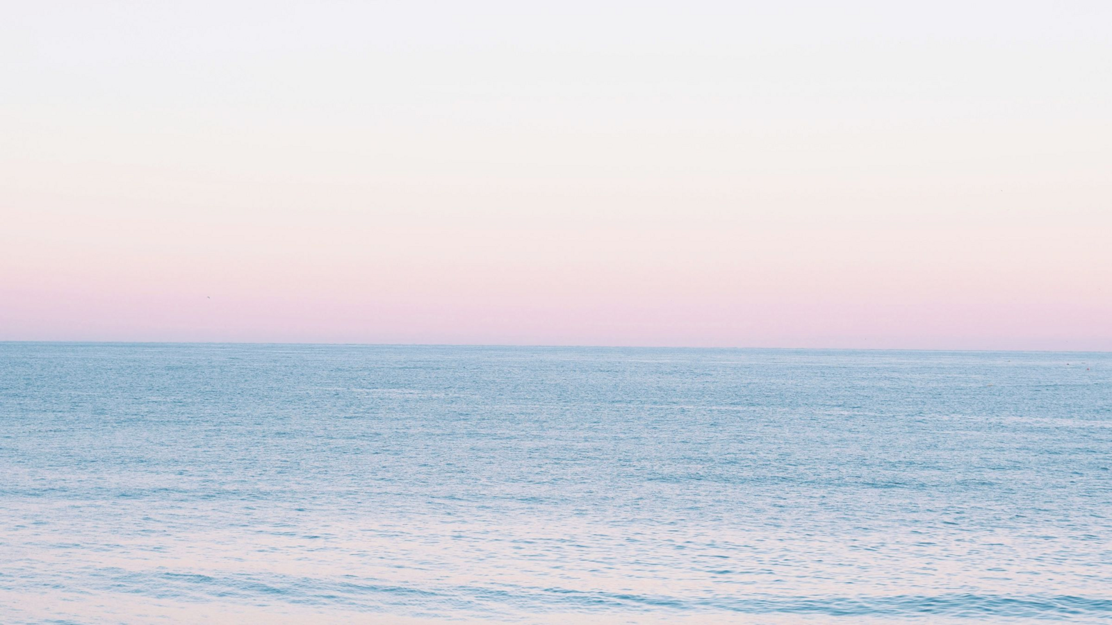 Woman stands in a field surrounded by mountains with her hands stretched to the sky.