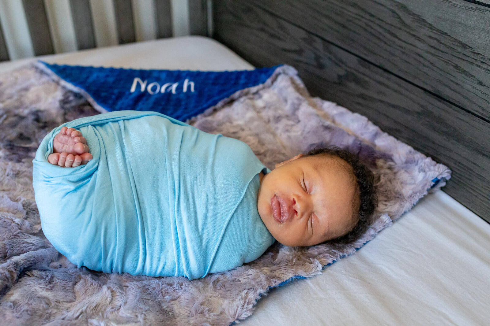 A newborn boy wrapped in blue in his crib in Woodbridge.