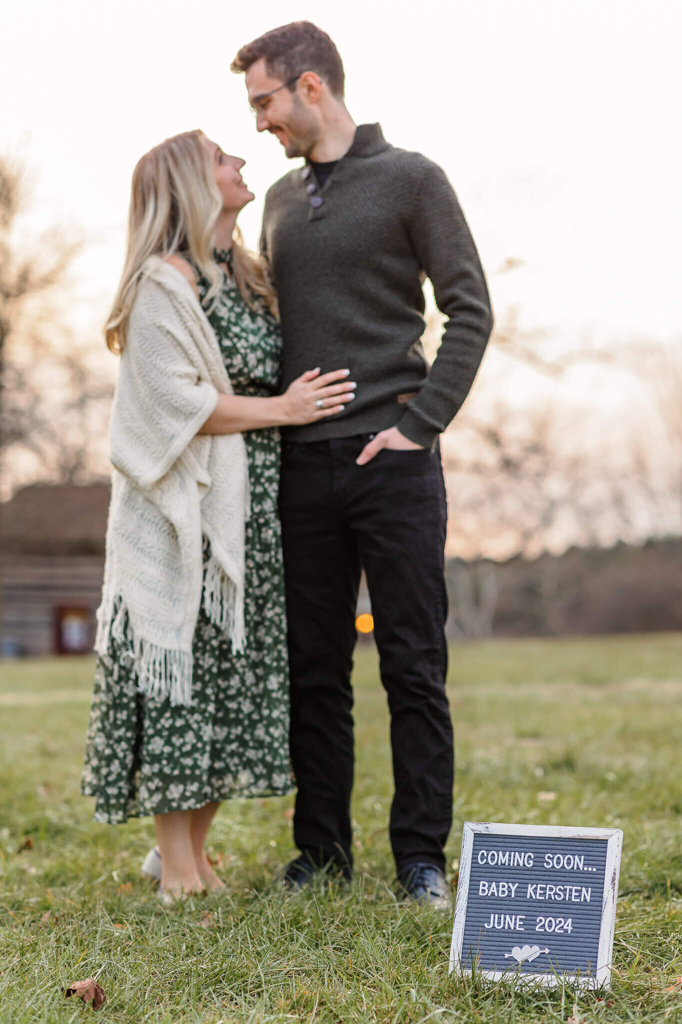 A sign announcing a pregnancy with mom and dad in the background.