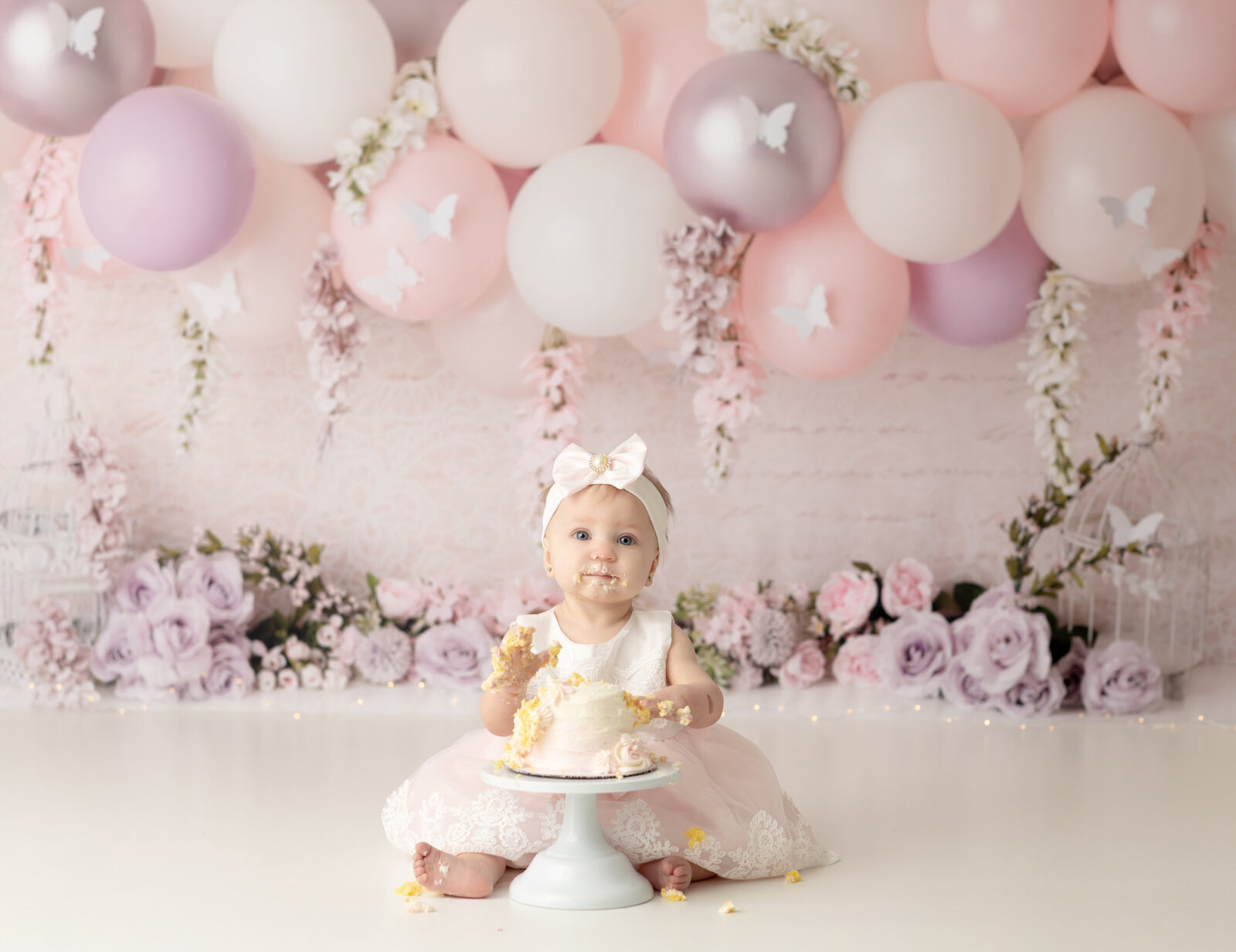 one year old girl in pink and white dress eating cake for cake smash photography