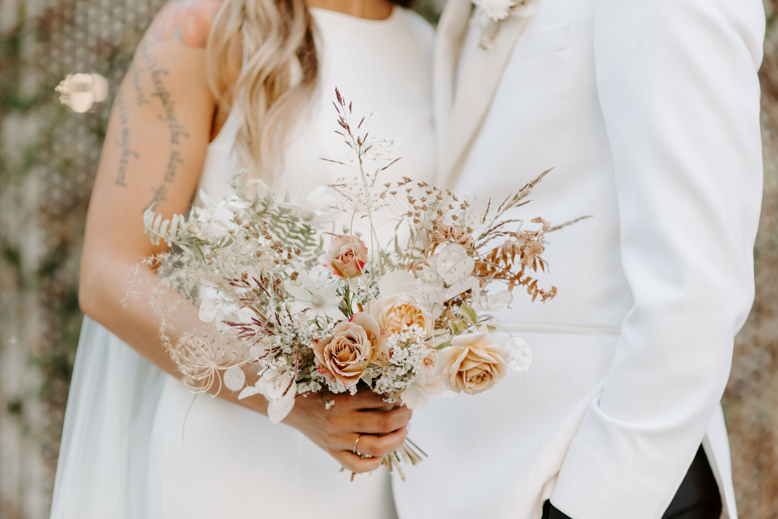 A small bridal bouquet is held by a bride who is close to her groom in Tulsa, Oklahoma.