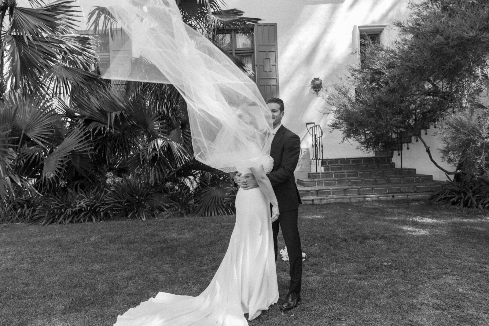 Bride and groom hugging with veil flying around them