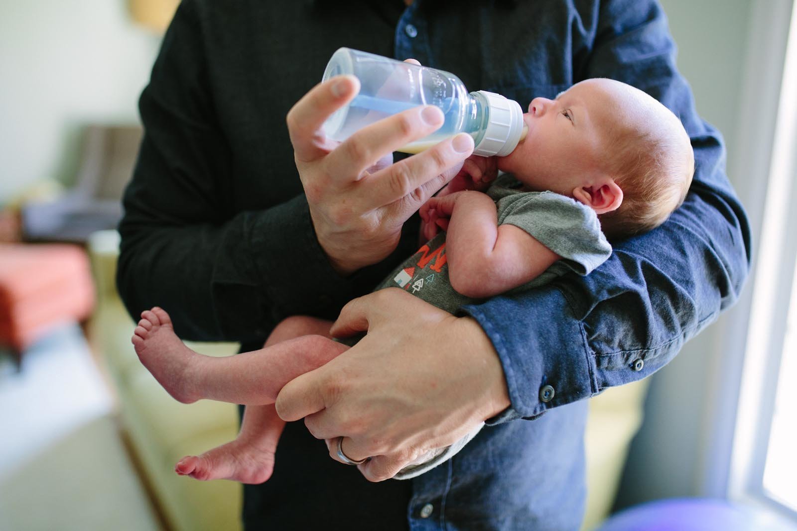 dad holding and bottle-feeding his newborn daughter