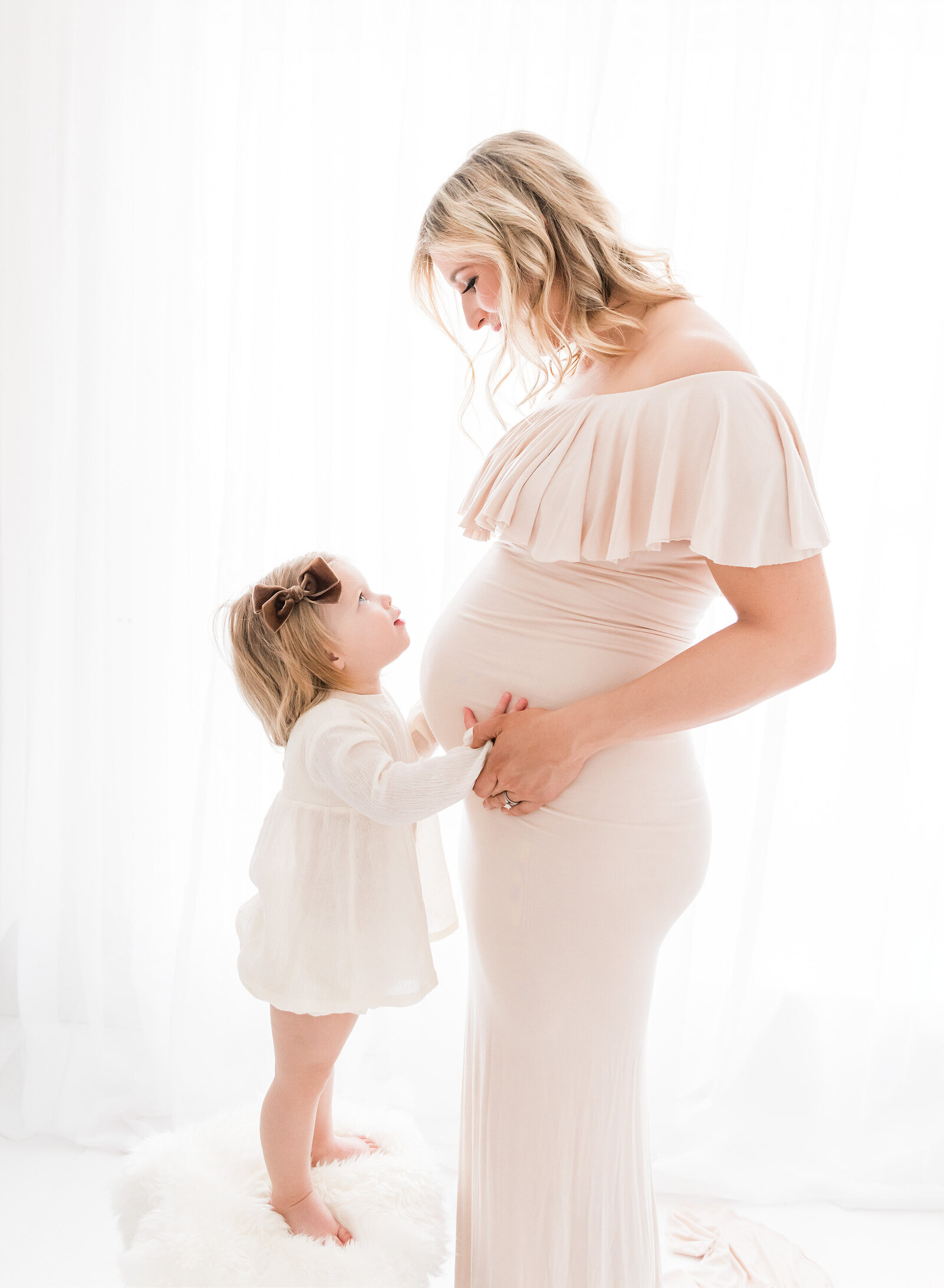 cute little girl holding her mommas pregnant belly
