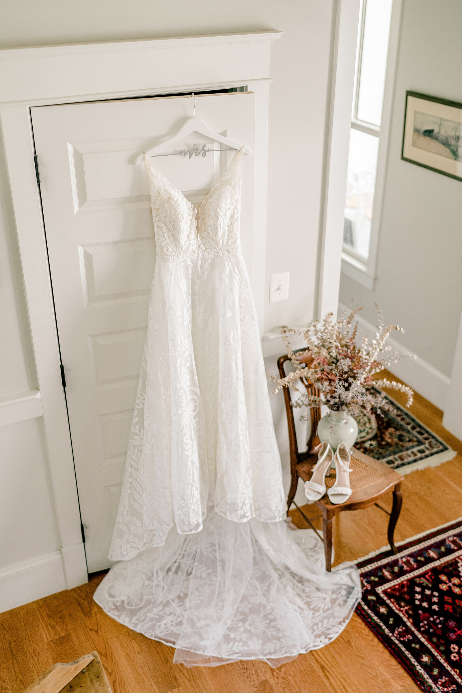 A wedding dress hanging in the foyer of a farmhouse during a wedding at Blue Hill Farm in Northern Virginia