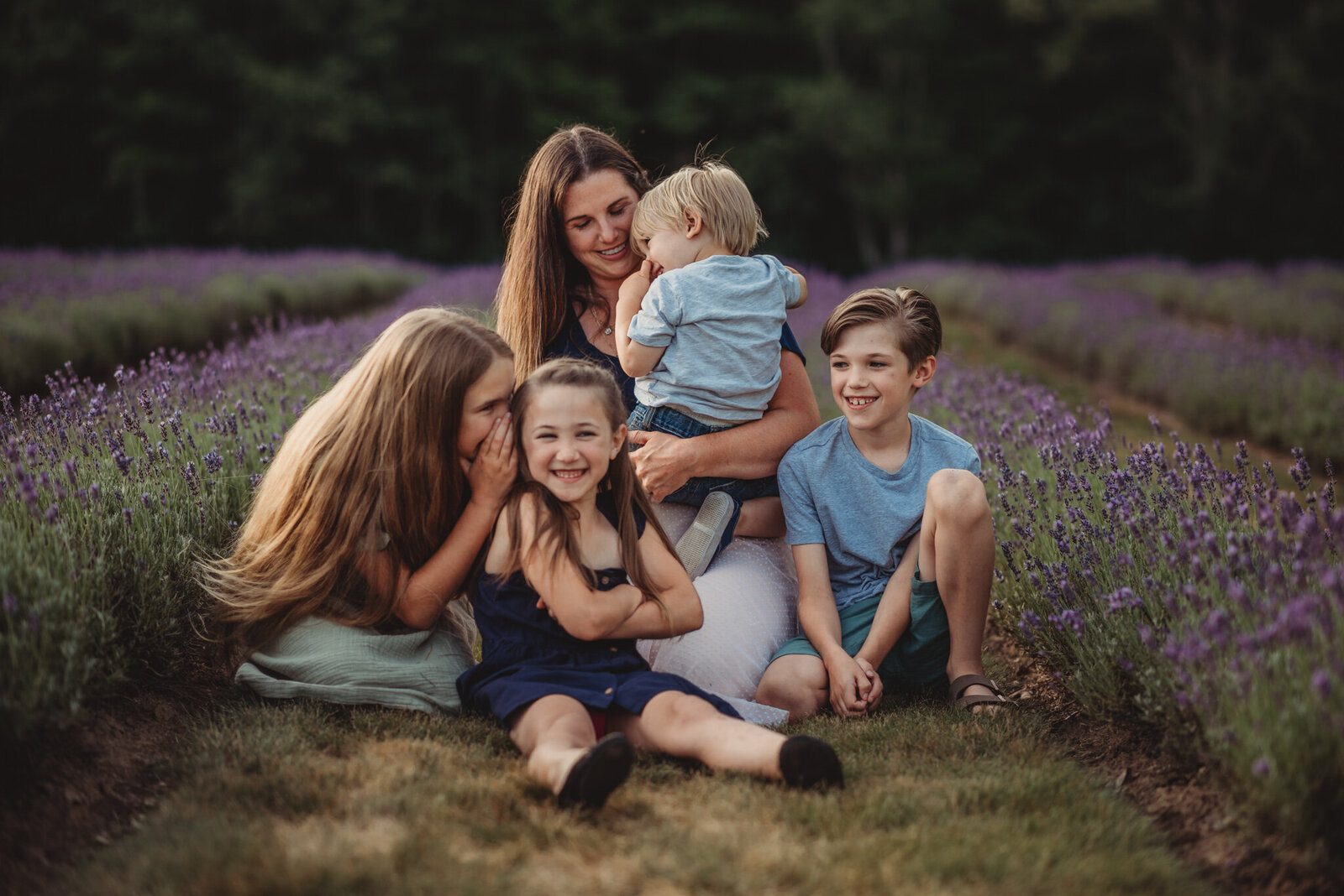 Mother sitting with her four young children in a lavender field