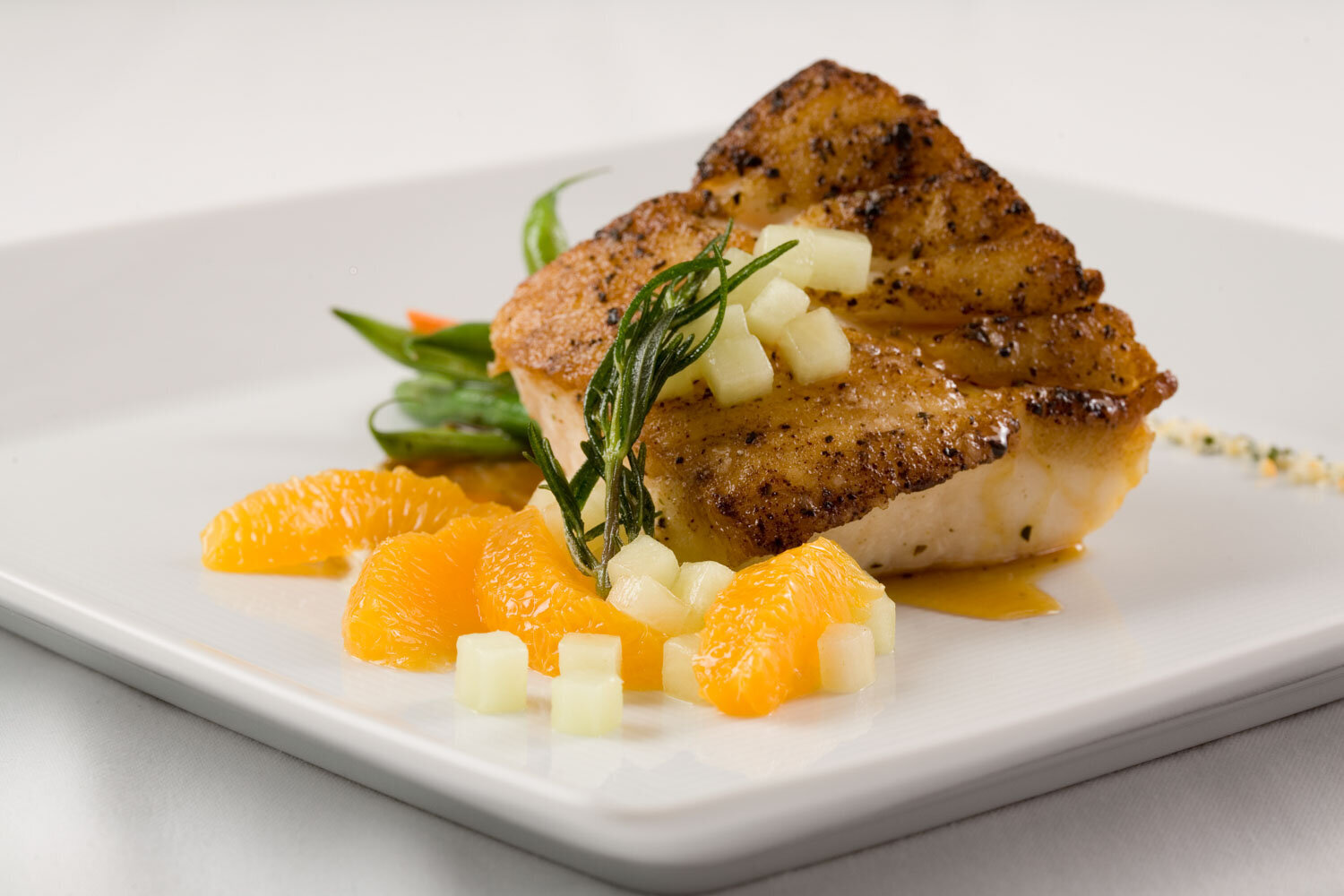 Seared fish fillet with citrus segments, diced melon, and green beans