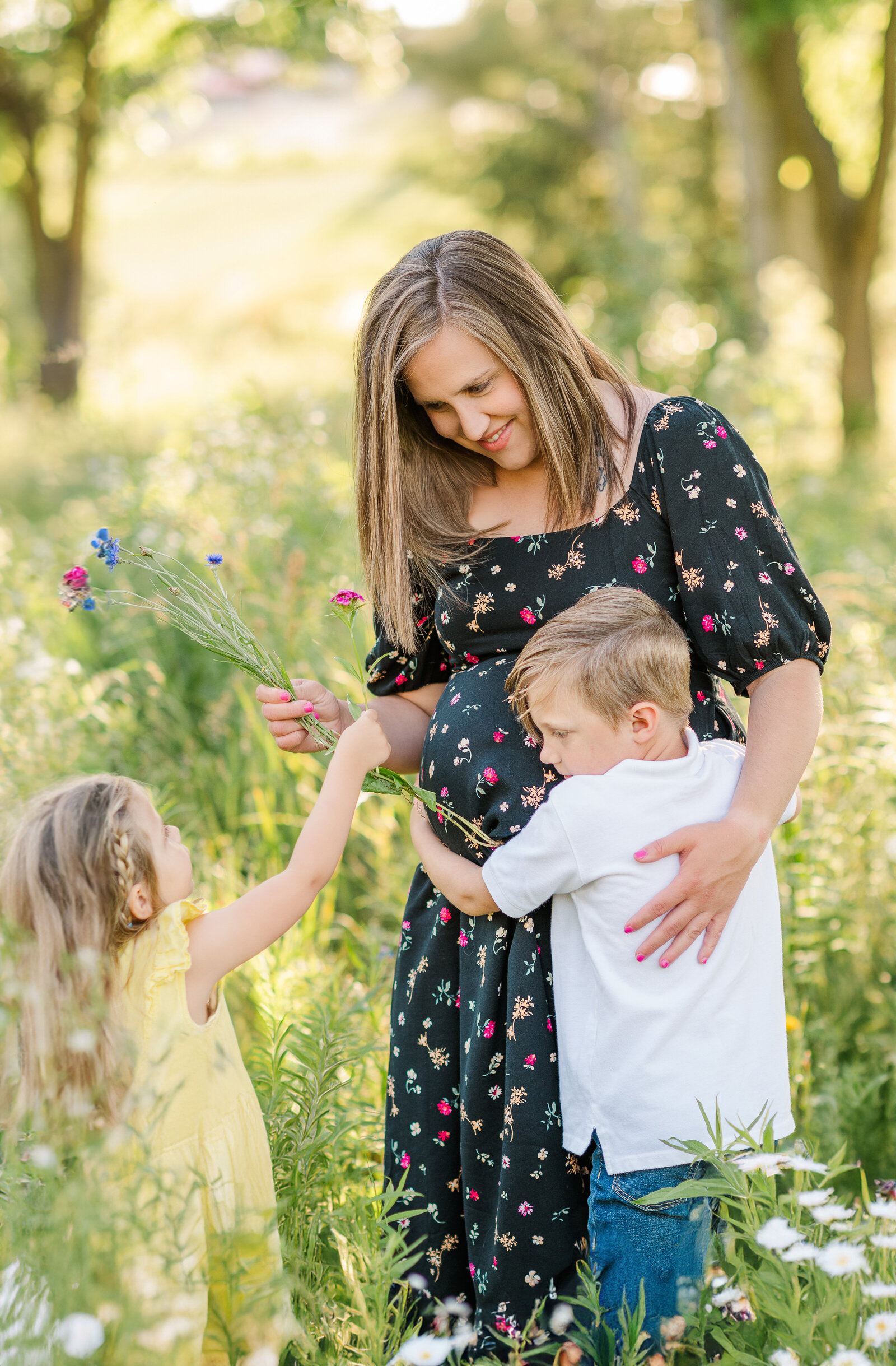 pregnant mother posing with two children in a wildflower field by york pa photographer