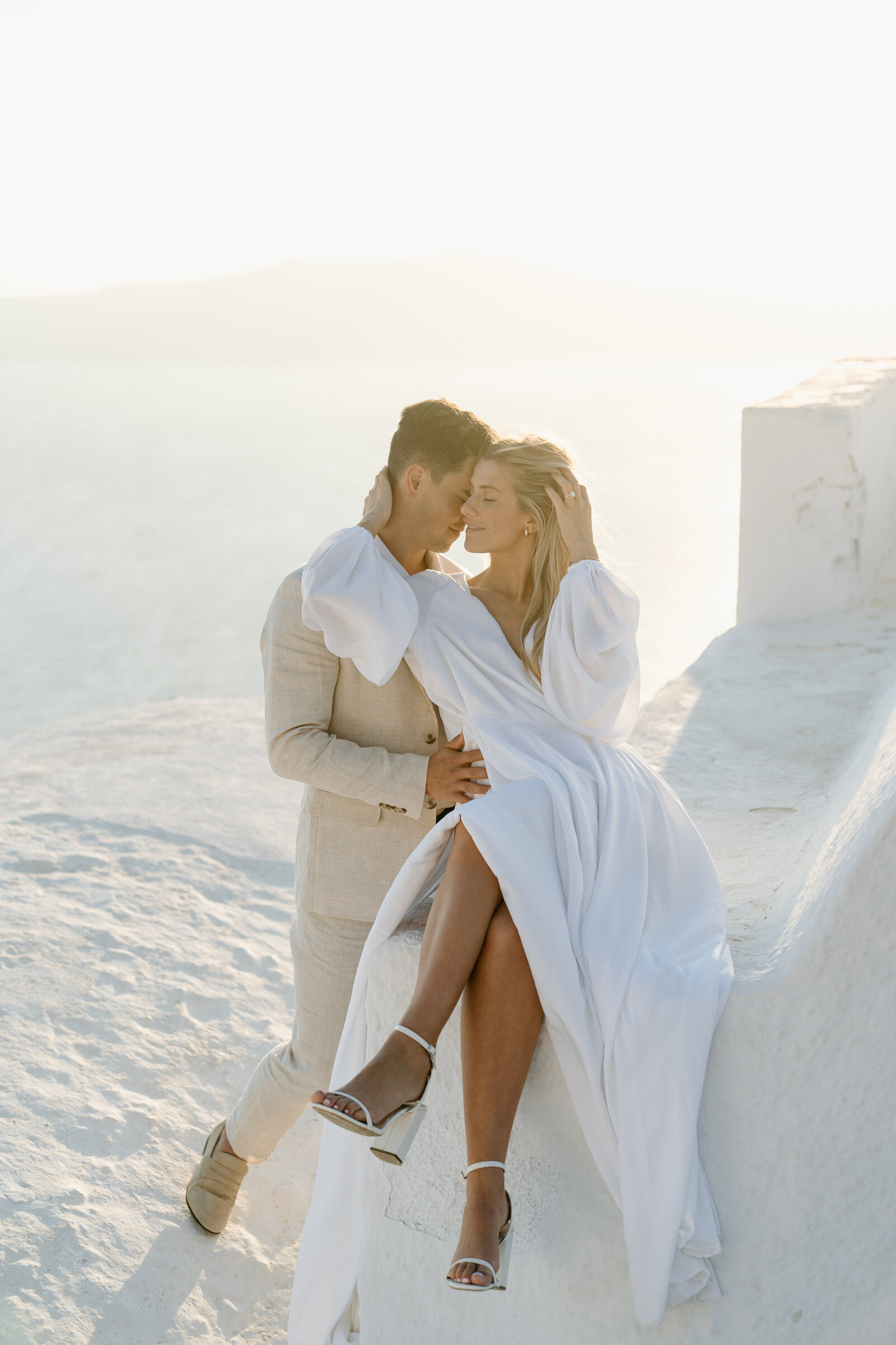 Couple in wedding attire elopeing on top of an iconic white dome church in Santorini Greece