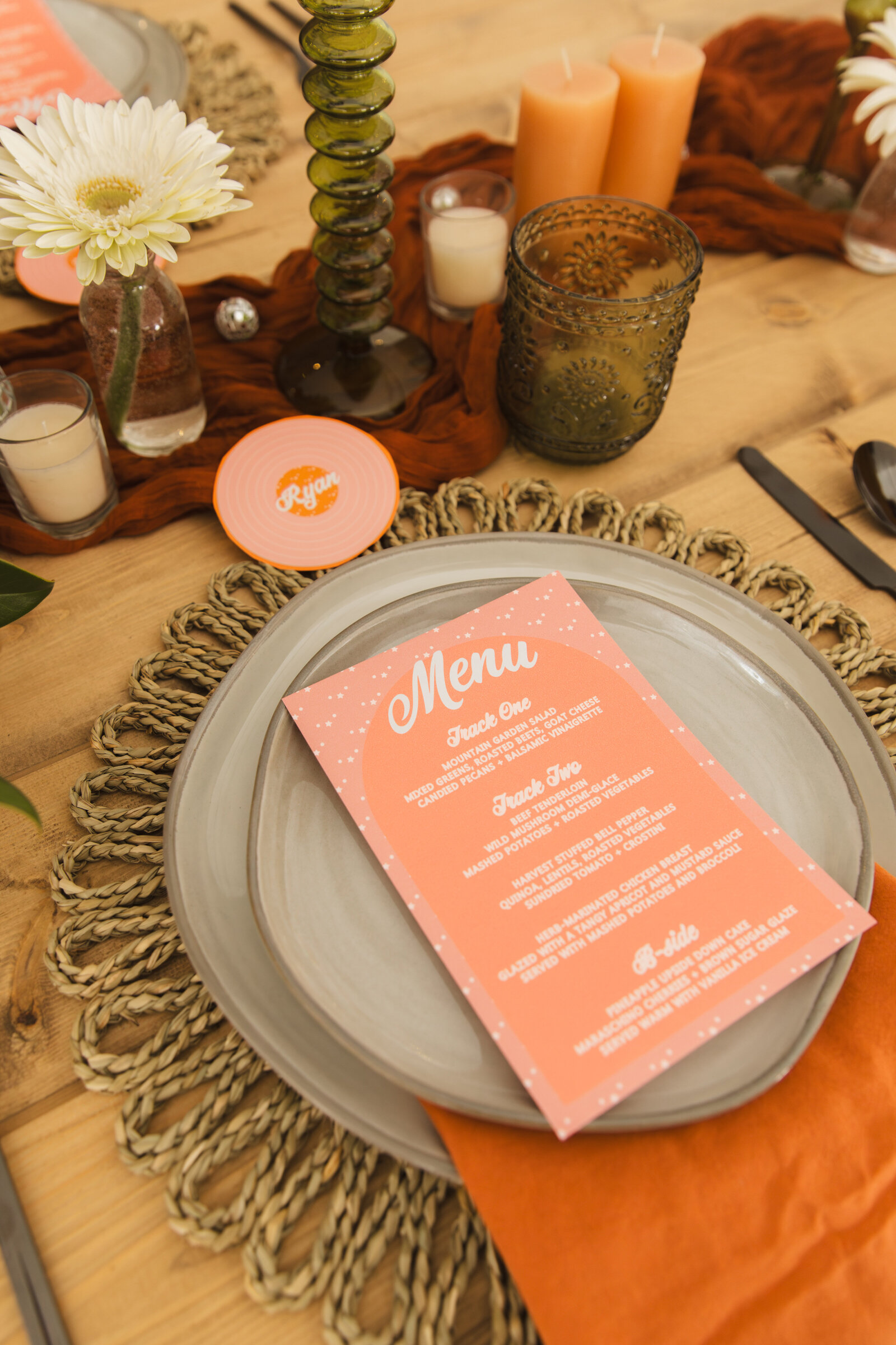 A wedding place card shaped like a record with a terra cotta wedding menu on top of a wedding charger plate and terra cotta linen.