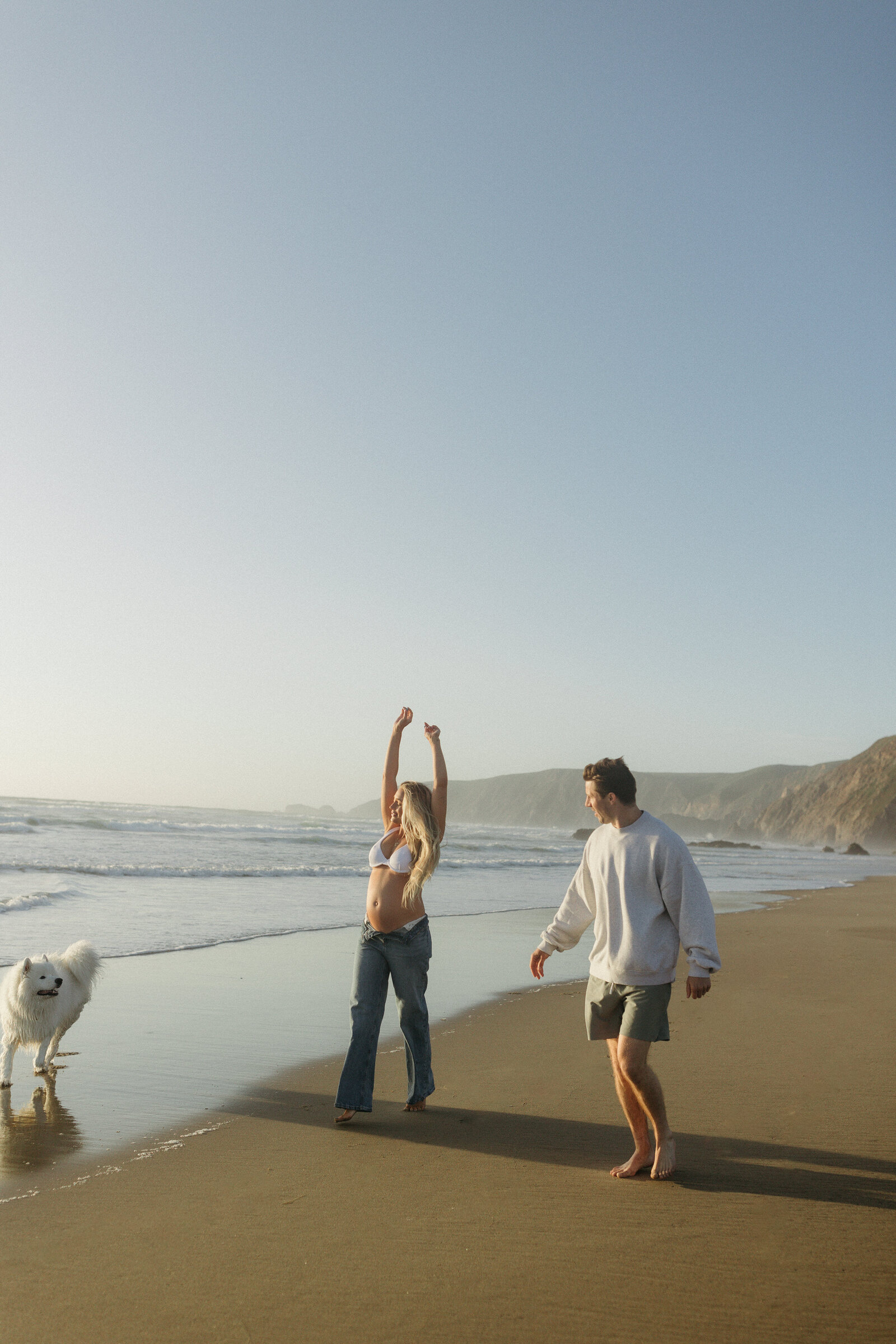 Couple playing with dog in the water during Point Reyes Beach maternity session