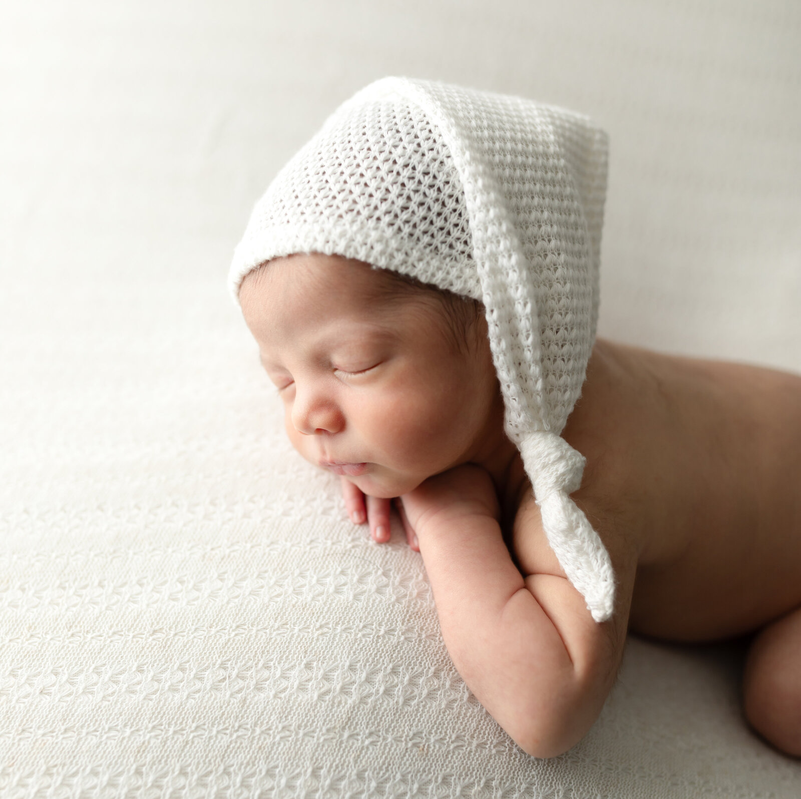 newborn baby boy in white hat posed for studio portraits cleveland newborn photographer
