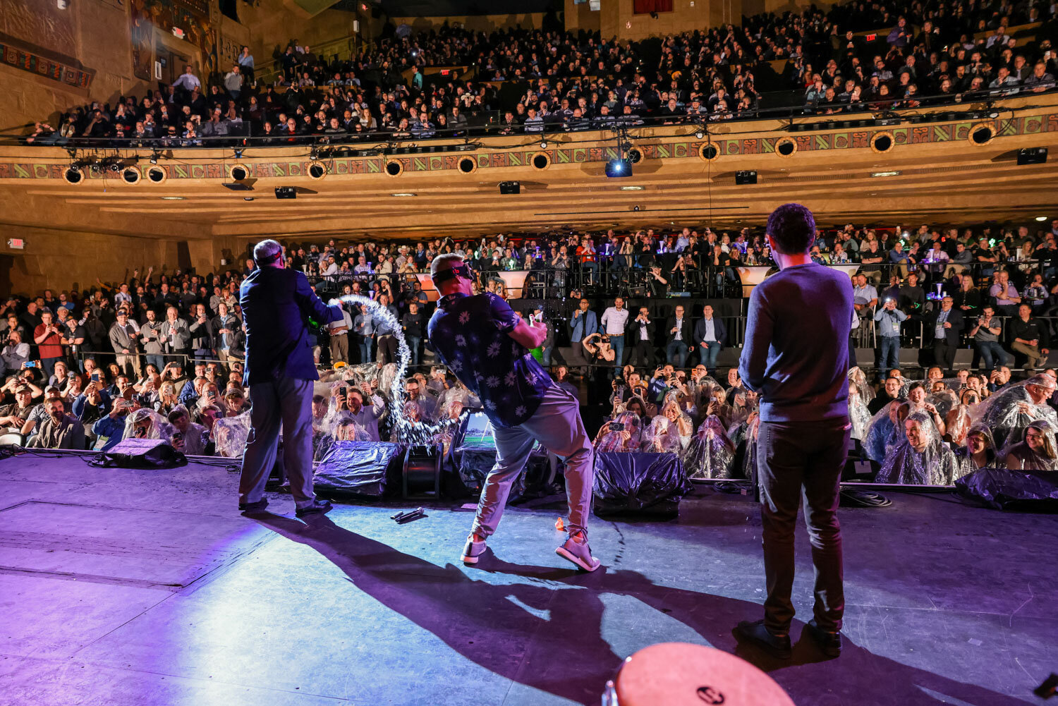 Performer spraying champagne on stage in front of a packed theater audience