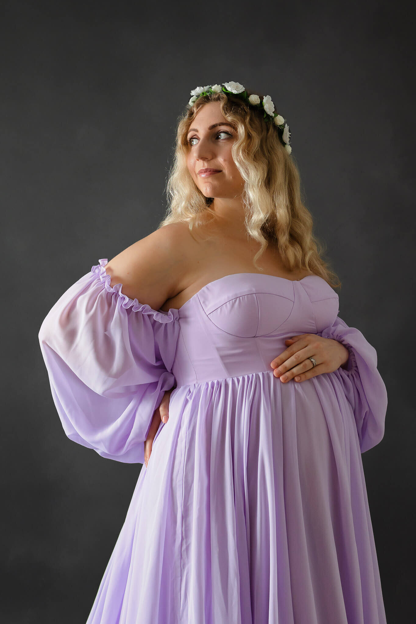 A pregnant mom in a purple dress posing in a Gainesville studio.