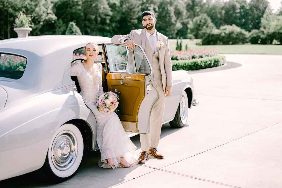 photo of bride and groom posing with old sports car