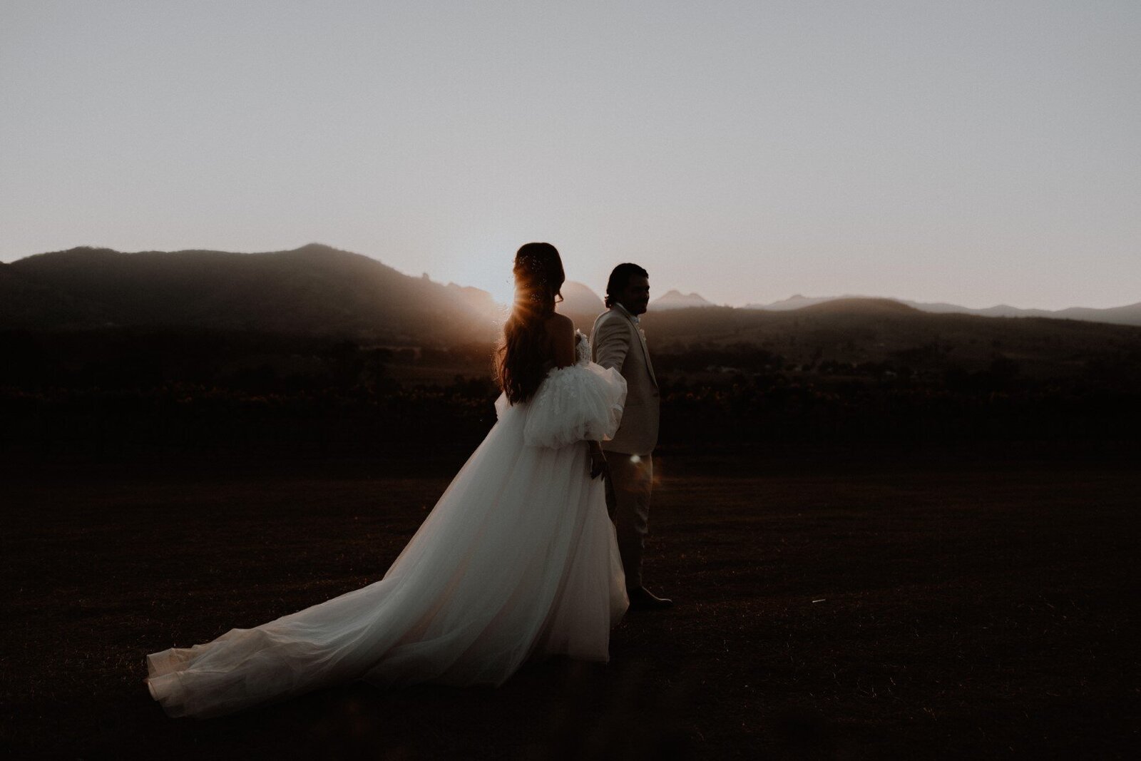 bride and groom walking at sunset near mountains