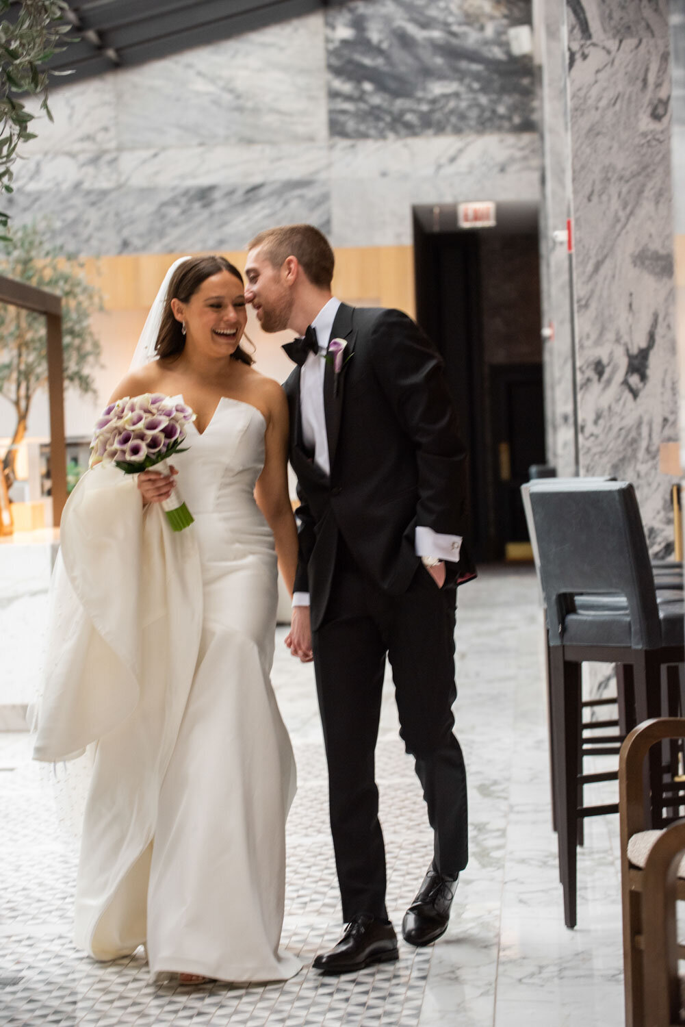 A bride and groom standing next to each other in front of an exit sign