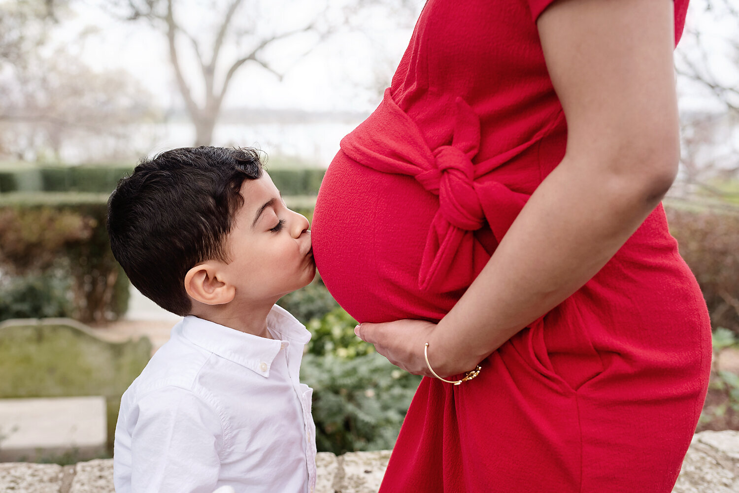 Young boy kissing his mother's belly at her lifestyle maternity session.