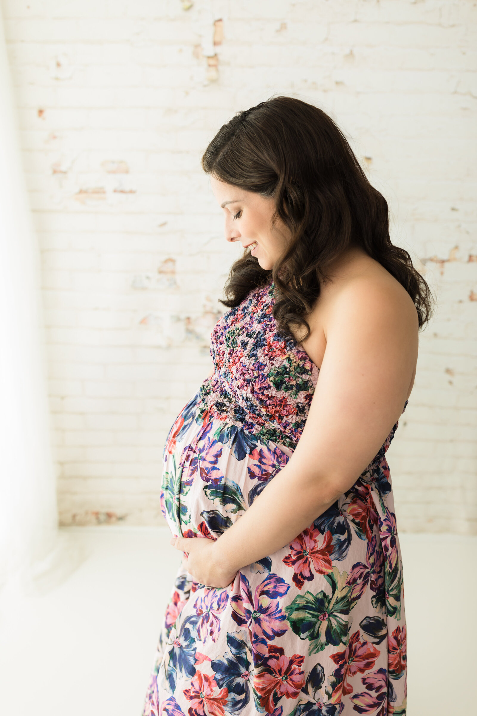 pregnant mother holding belly in floral dress for photoshoot Cleveland maternity photographer