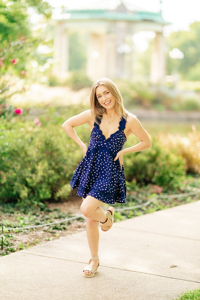 full body of senior with hands on hips smiling with out of focus pagoda in background