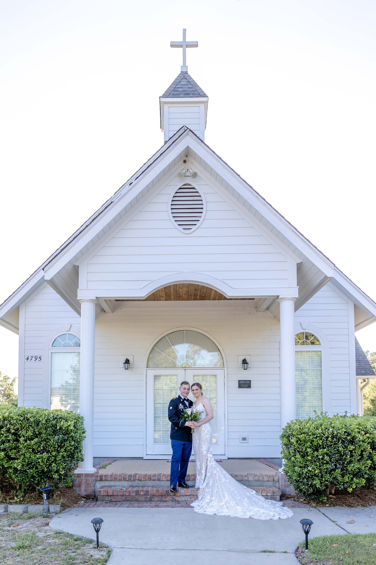 Newlyweds posing outside a charming chapel, showcasing their love and the beautiful architecture in Oak Island, NC.
