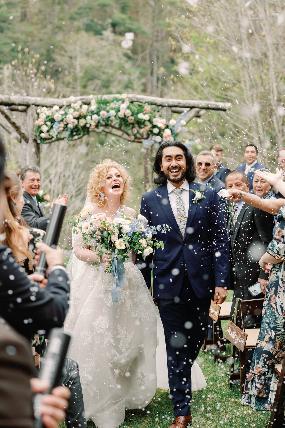 Bride and Groom laughing and  Exiting Ceremony while guests throw confetti