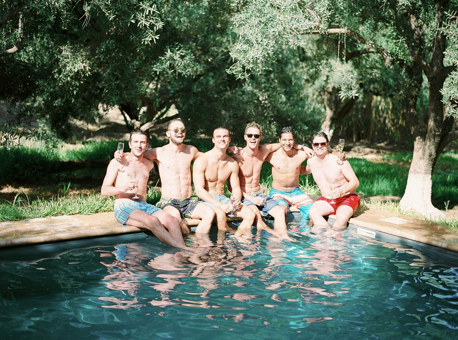 Groom and groomsmen hanging out at the pool during a wedding in Morocco