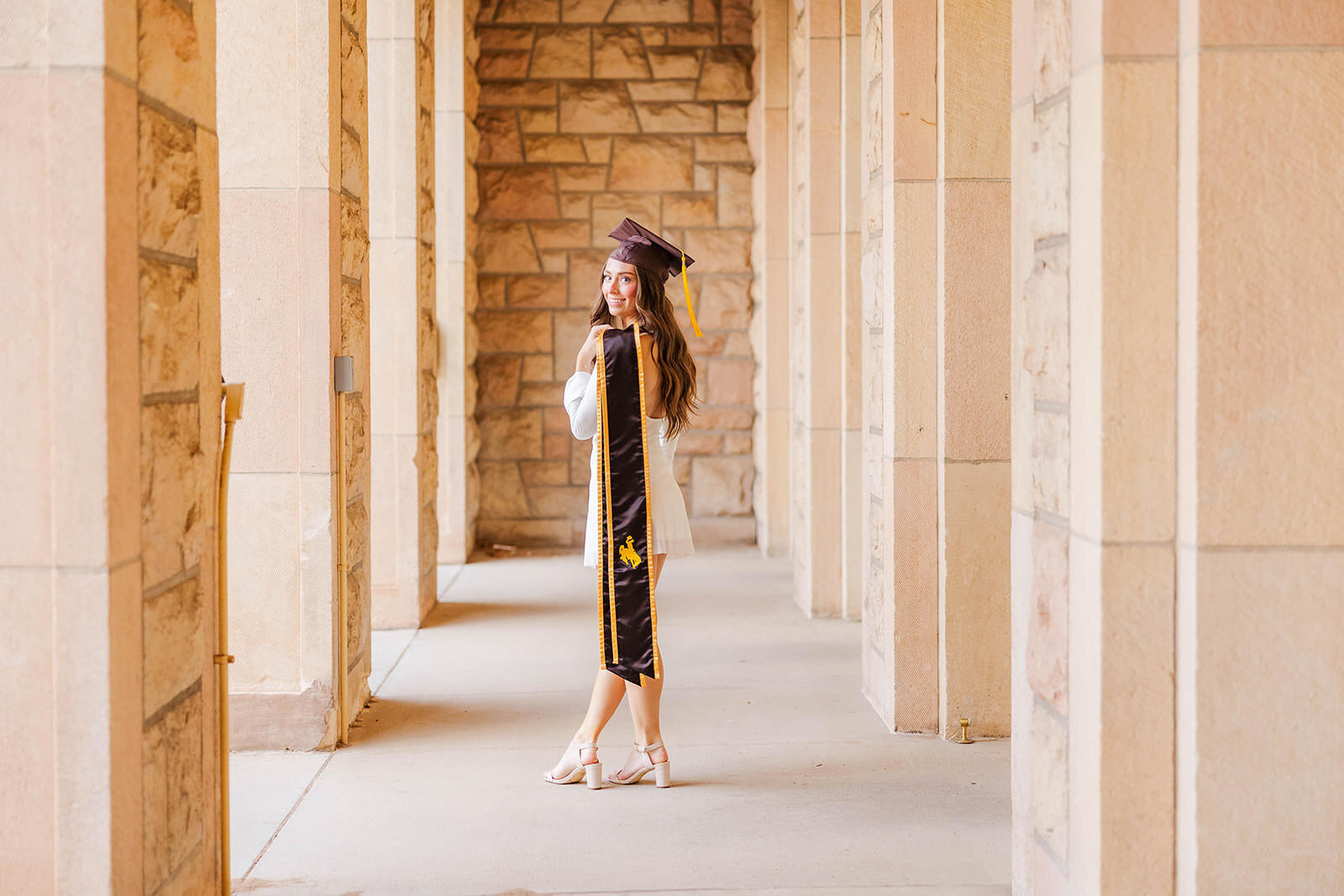 College graduate posing for her graduation photos at the University of Wyoming.