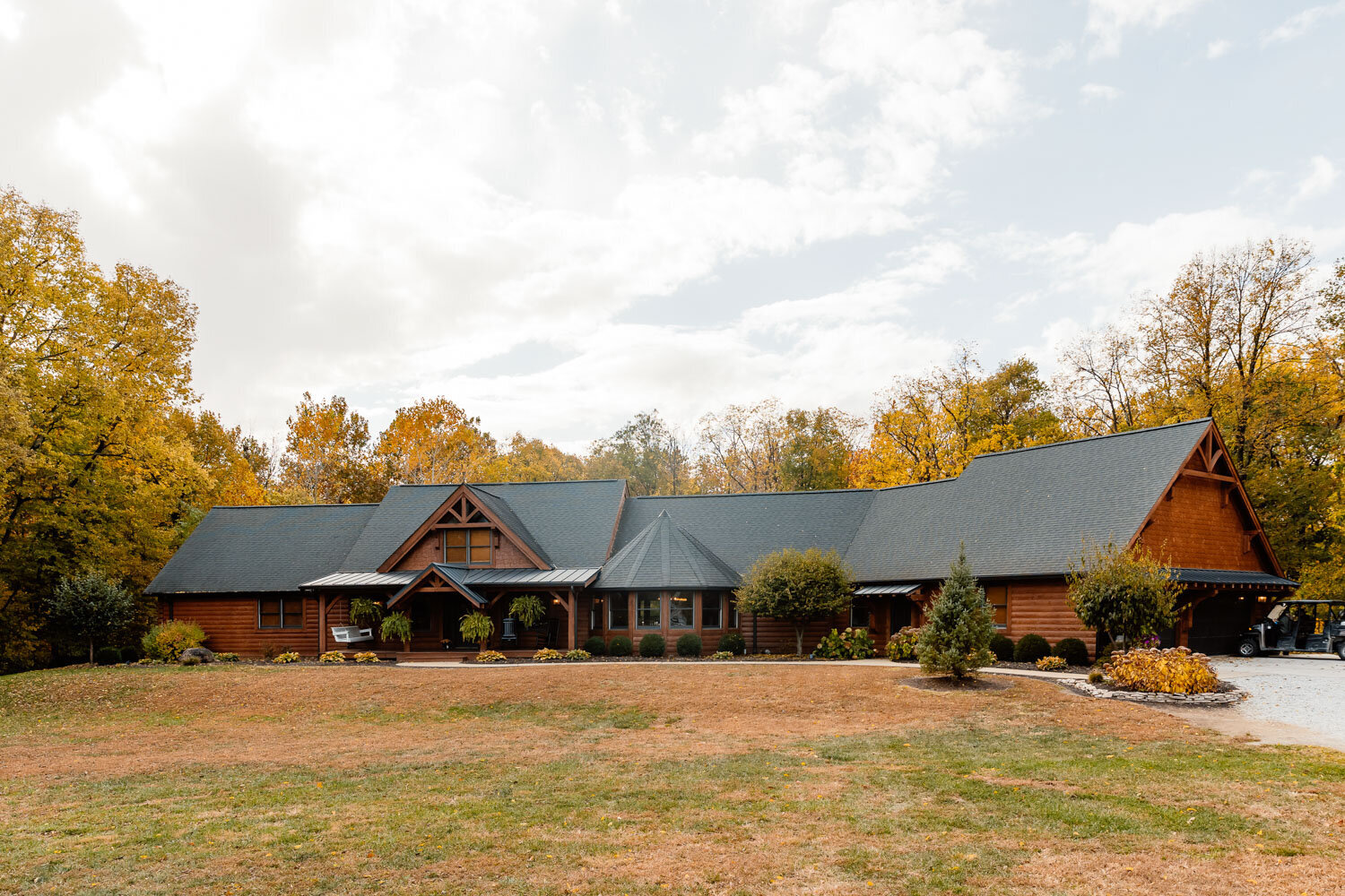 Charming cabin-style venue with a green lawn and autumn trees in the background