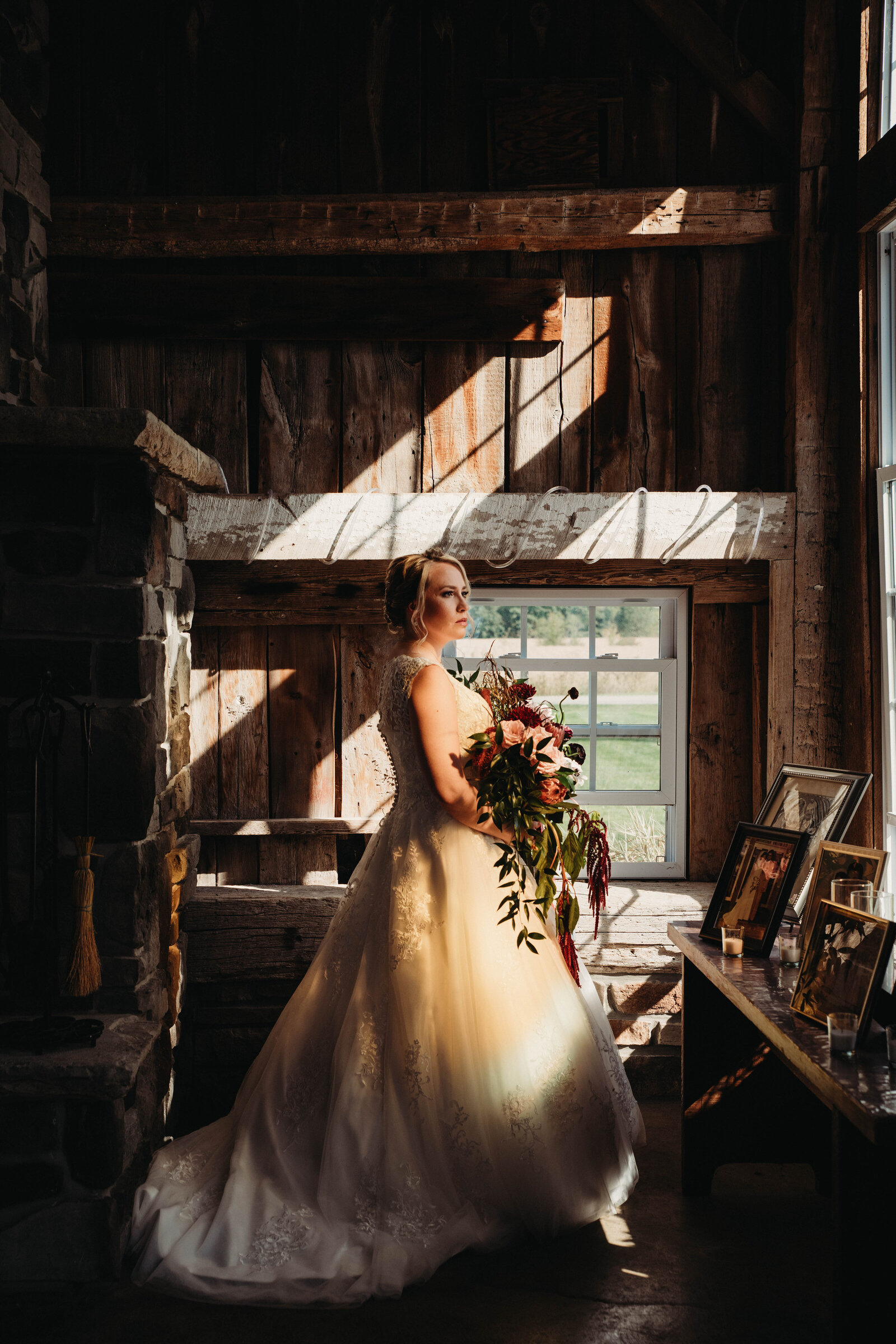 Bride stands in stained glass light at barn.