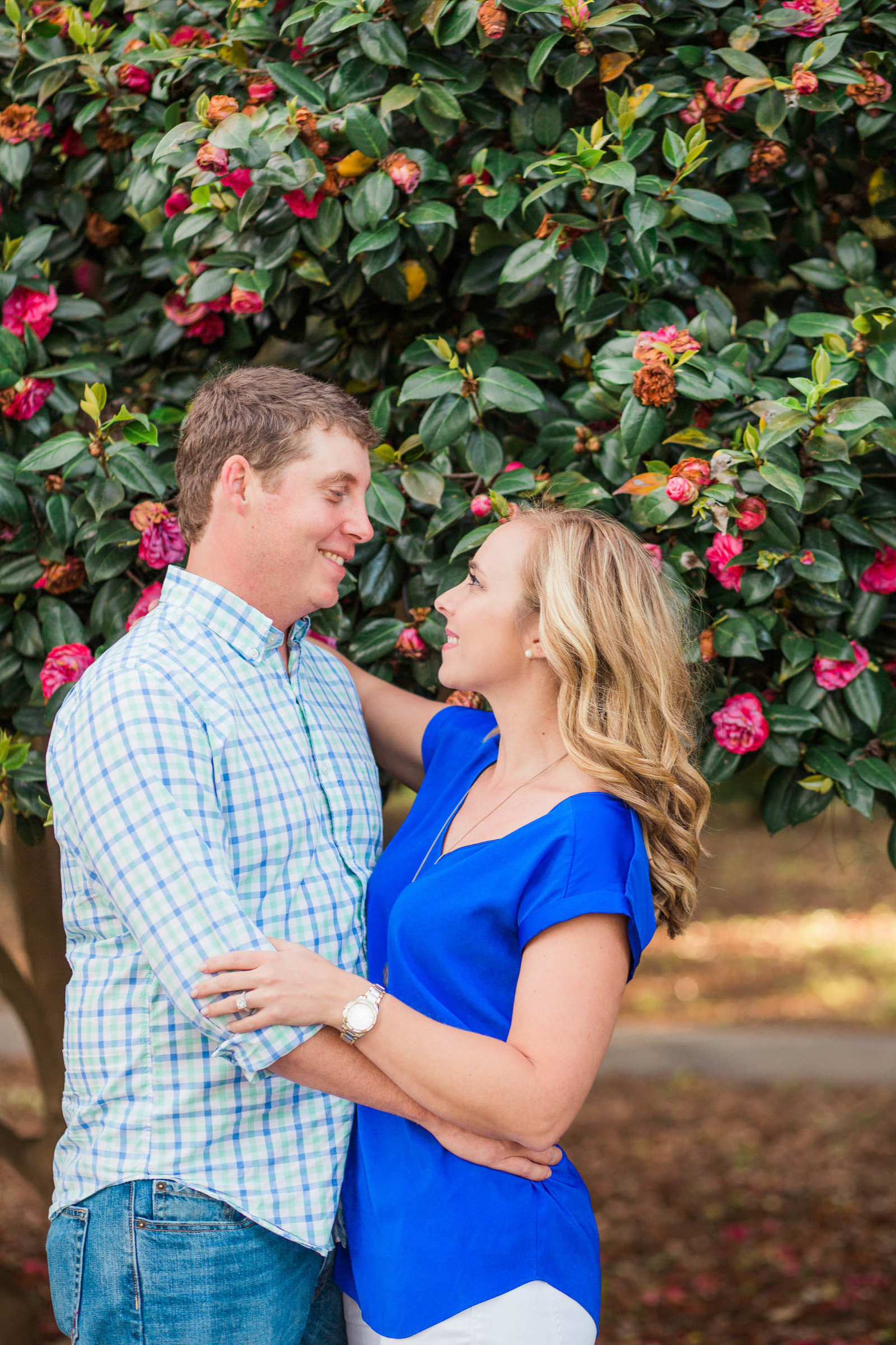 Engaged couple poses in front of tree with red flowers, Hampton Park, Charleston, South Carolina