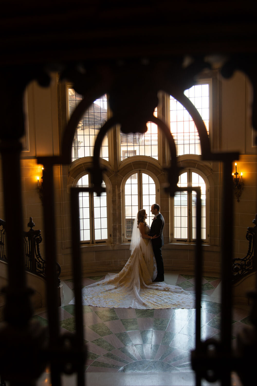 A bride and groom are standing in front of a window