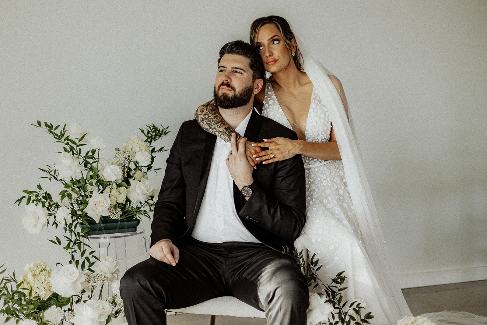 Bride and groom looking off into the distance with flowers to their left at The Landing Space