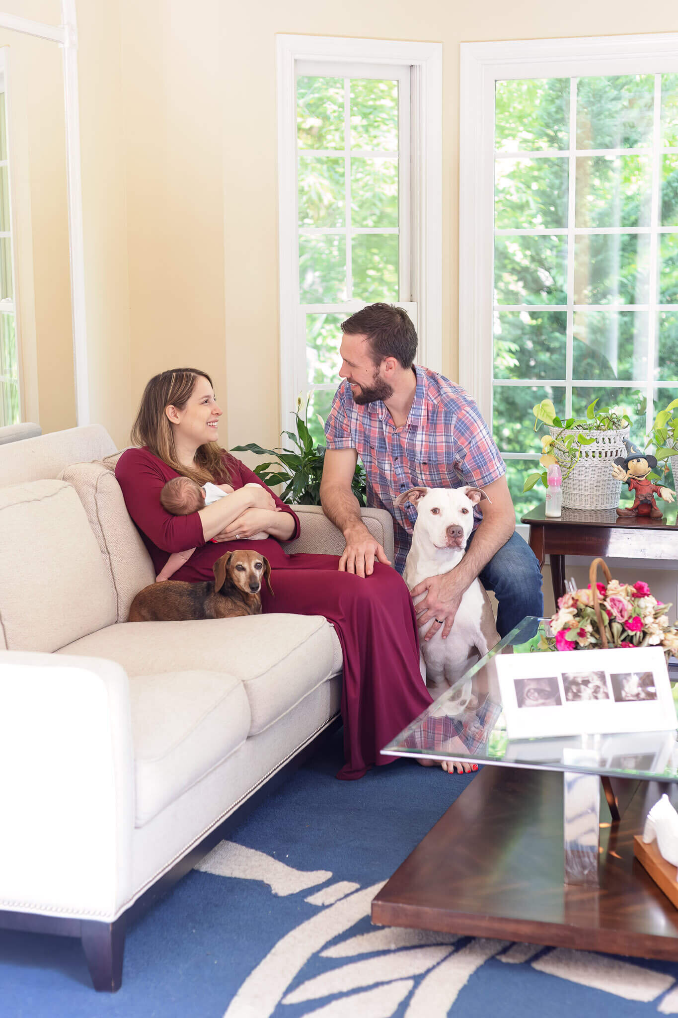 A couple with their newborn daughter and their two dogs sitting in their living room in their Manassas home.