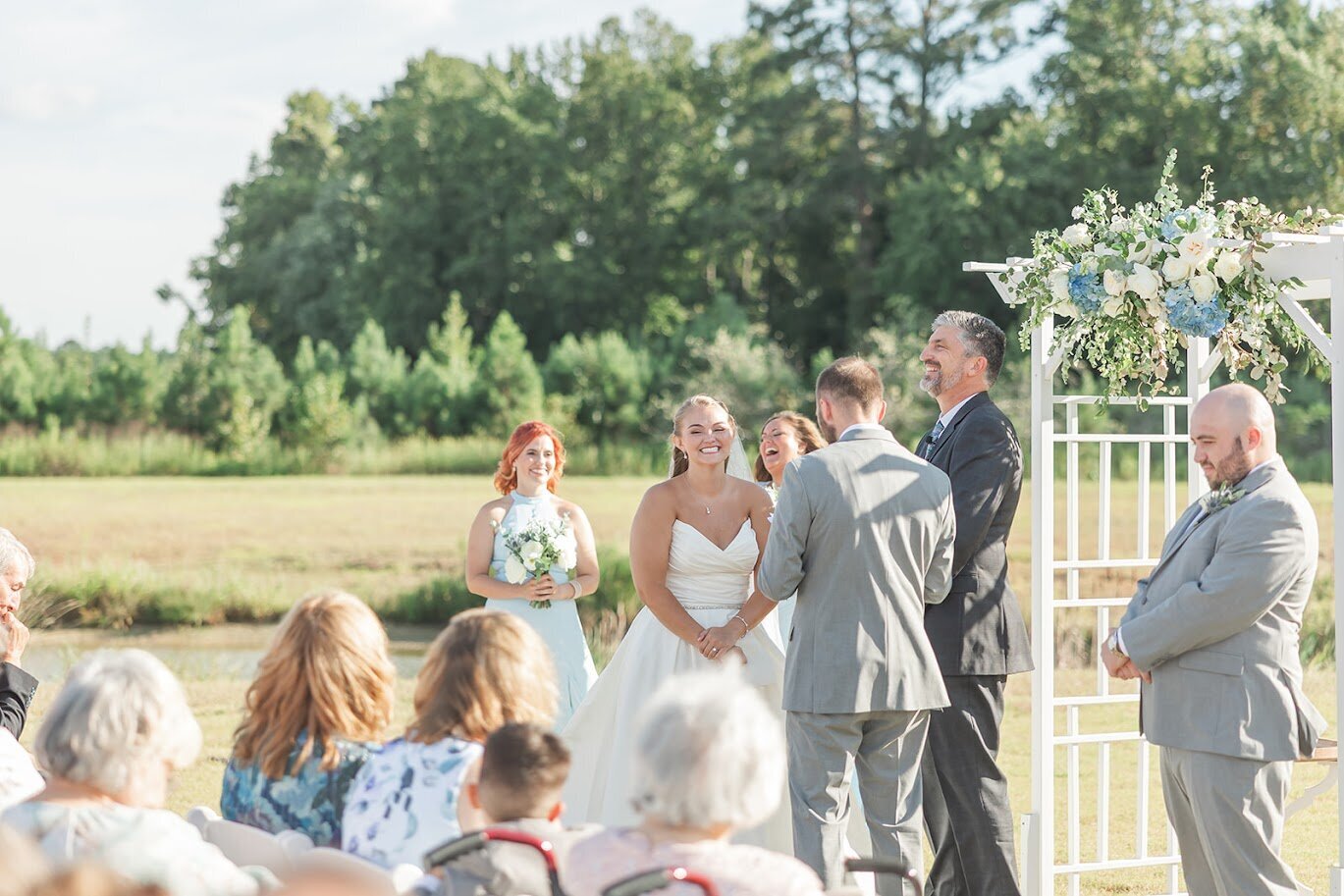Bride-Minister-Smiling-Arbor-Blue-White-Flowers-The-Legacy-At-Willow-Pond