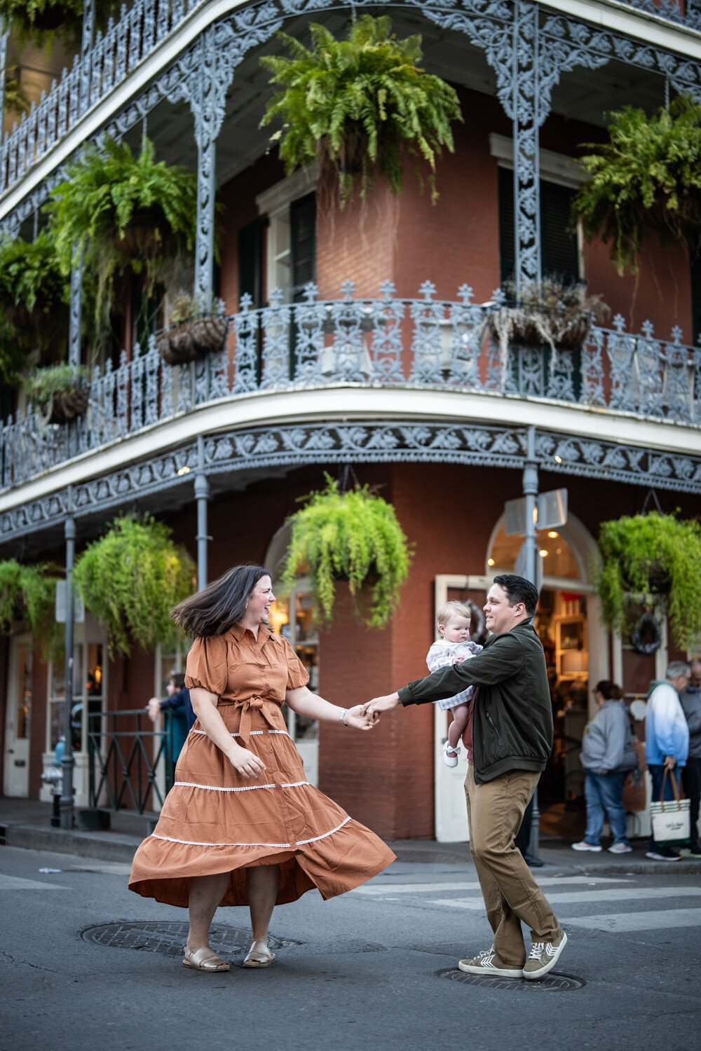 Couple dances in front of French Quarter building with ferns on balcony