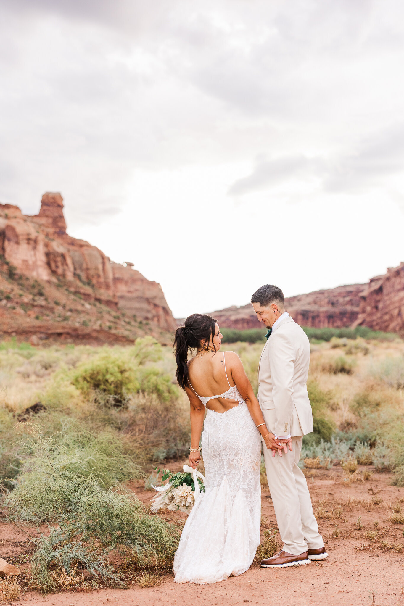 Bride and groom share a sweet laugh on their wedding day in front of the red earth venue scenic backdrop