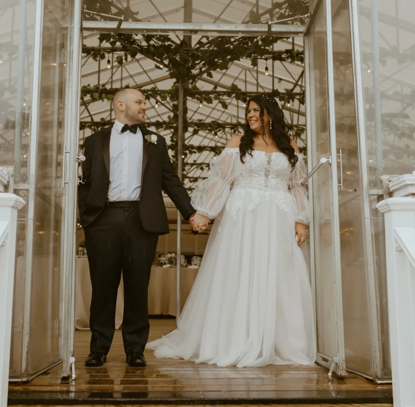 bride and groom hold hands while standing in an open doorway