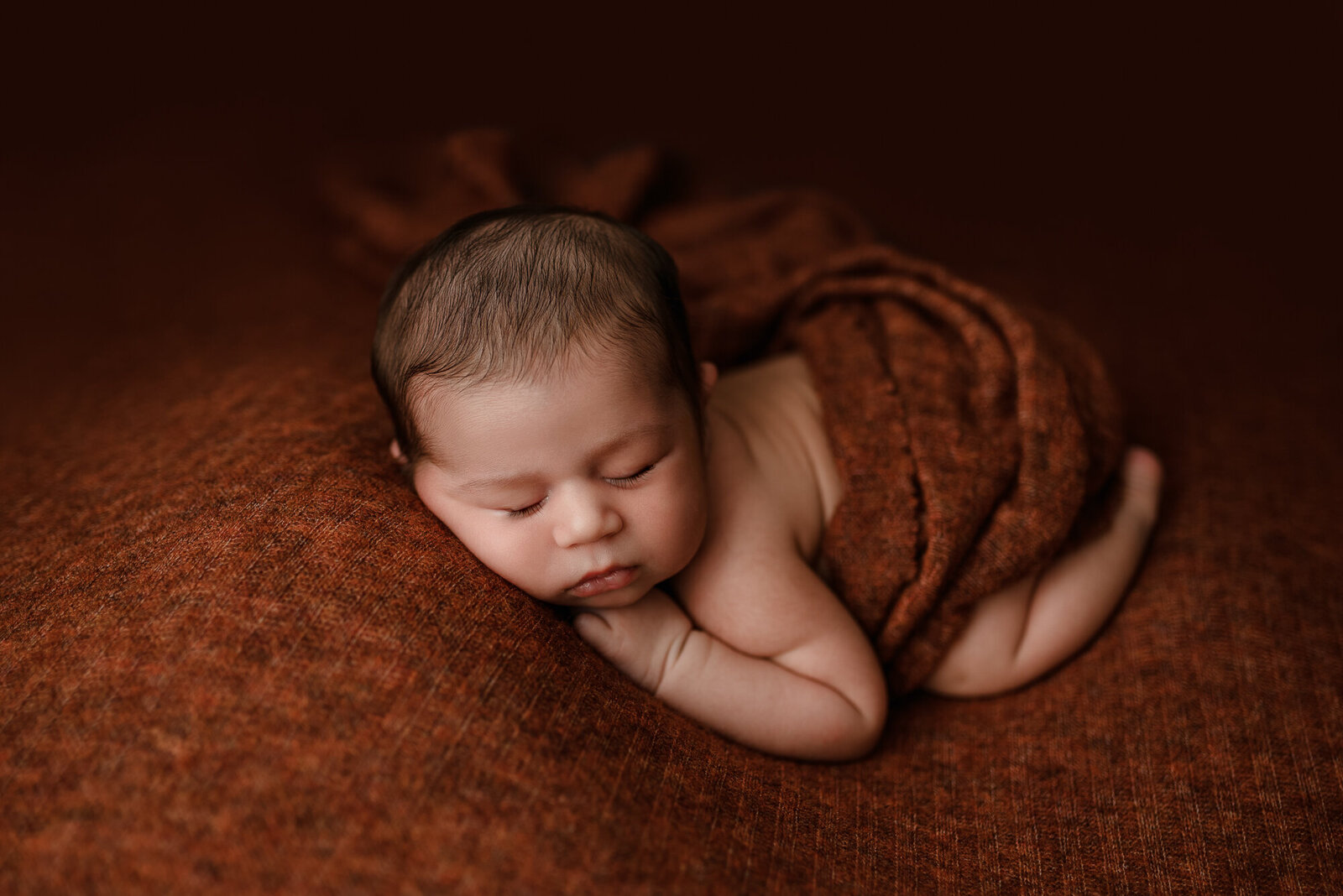 Studio photography of baby boy on rust orange bold and color