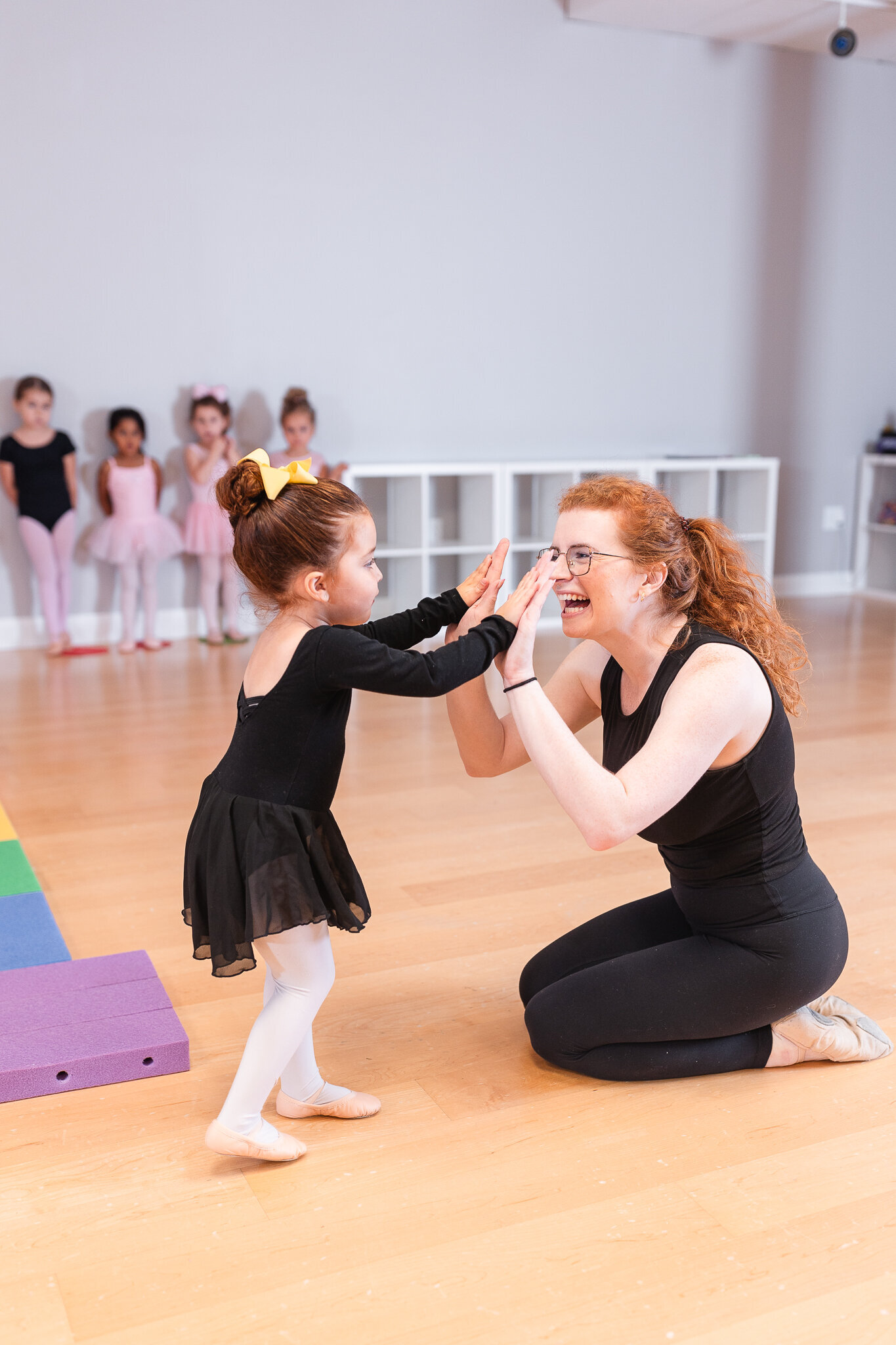 a teacher high fives their young ballet student