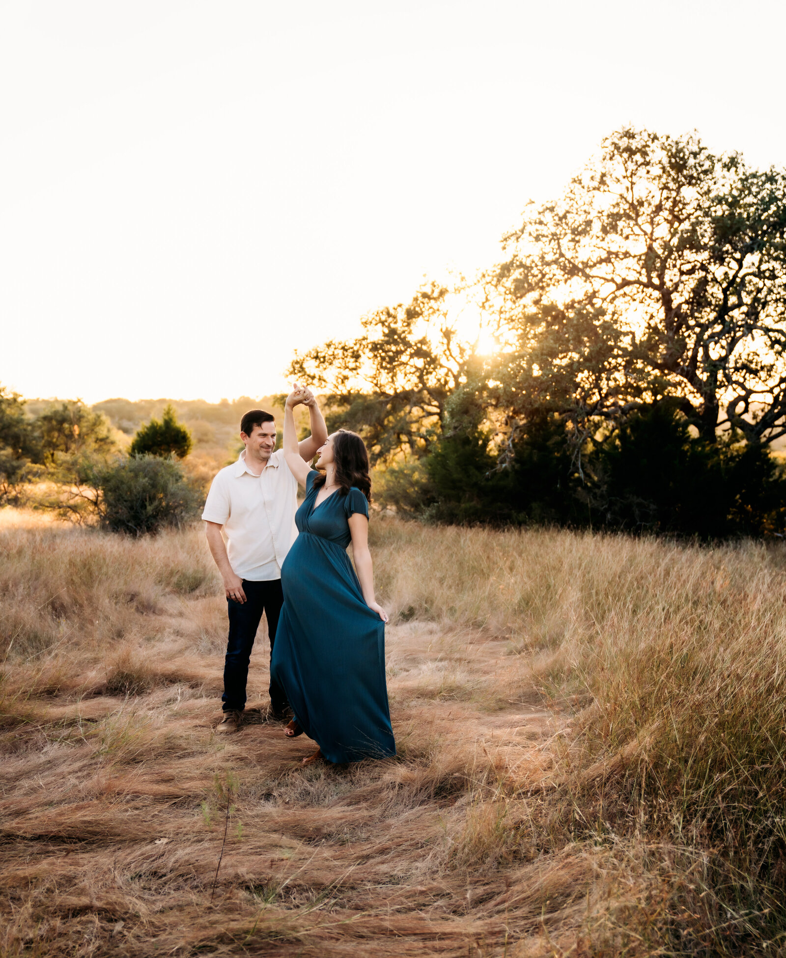 Maternity Photographer, man and pregnant wife dance in a dry field