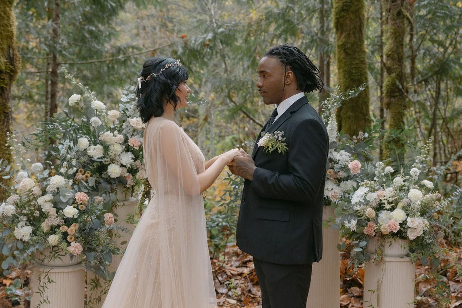 Bride and groom exchanging vows surrounded by floral arrangements